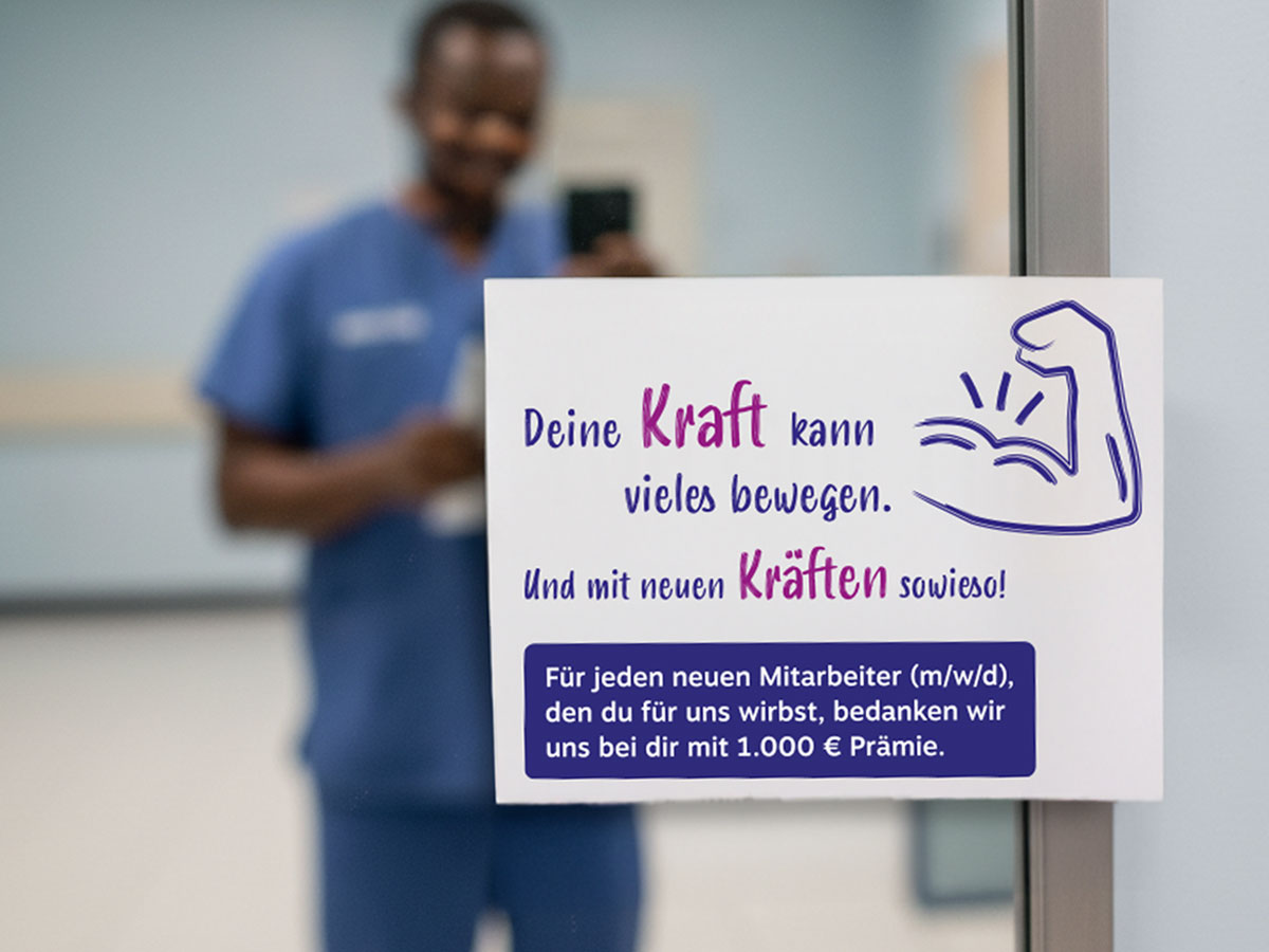 Dartellung Image Spiegelaufkleber Barmherzige Schwestern zur Bewerbung des "Mitarbeiter werben Mitarbeiter" Programms zu sehen ist der Aufkleber und ein Mitarbeiter macht ein Selfie im Spiegel mit dem Aufkleber - für neu geworbene Mitarbeiter erhät man eine Prämie