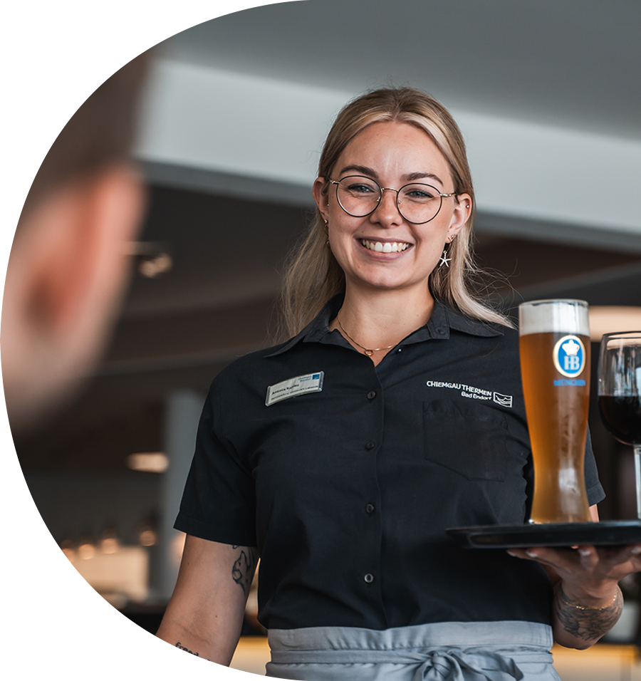 Gesundheitswelt Chiemgau Referenzkunde von twentyfourtalents Ansicht einer freundlichen Mitabrfeiterin die ein gesundes Weißbier serviert